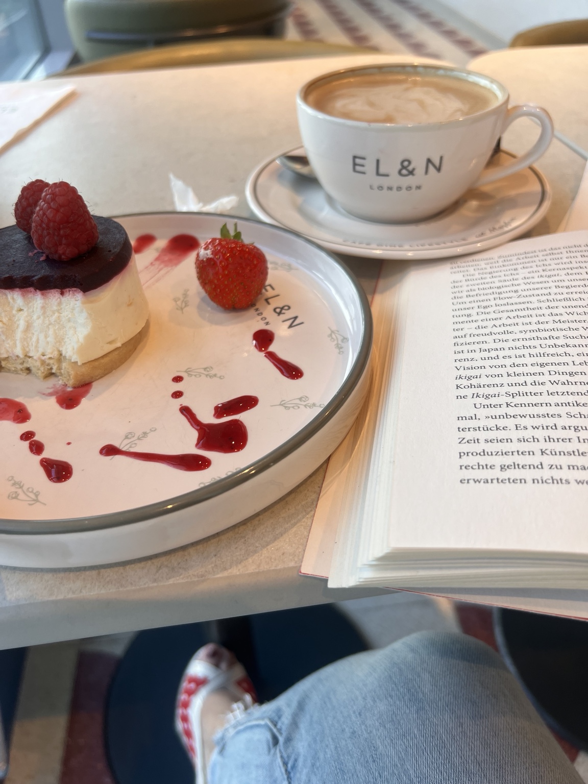 Kaffee, Kuchen und ein aufgeschlagenes Buch im EL&N Café.