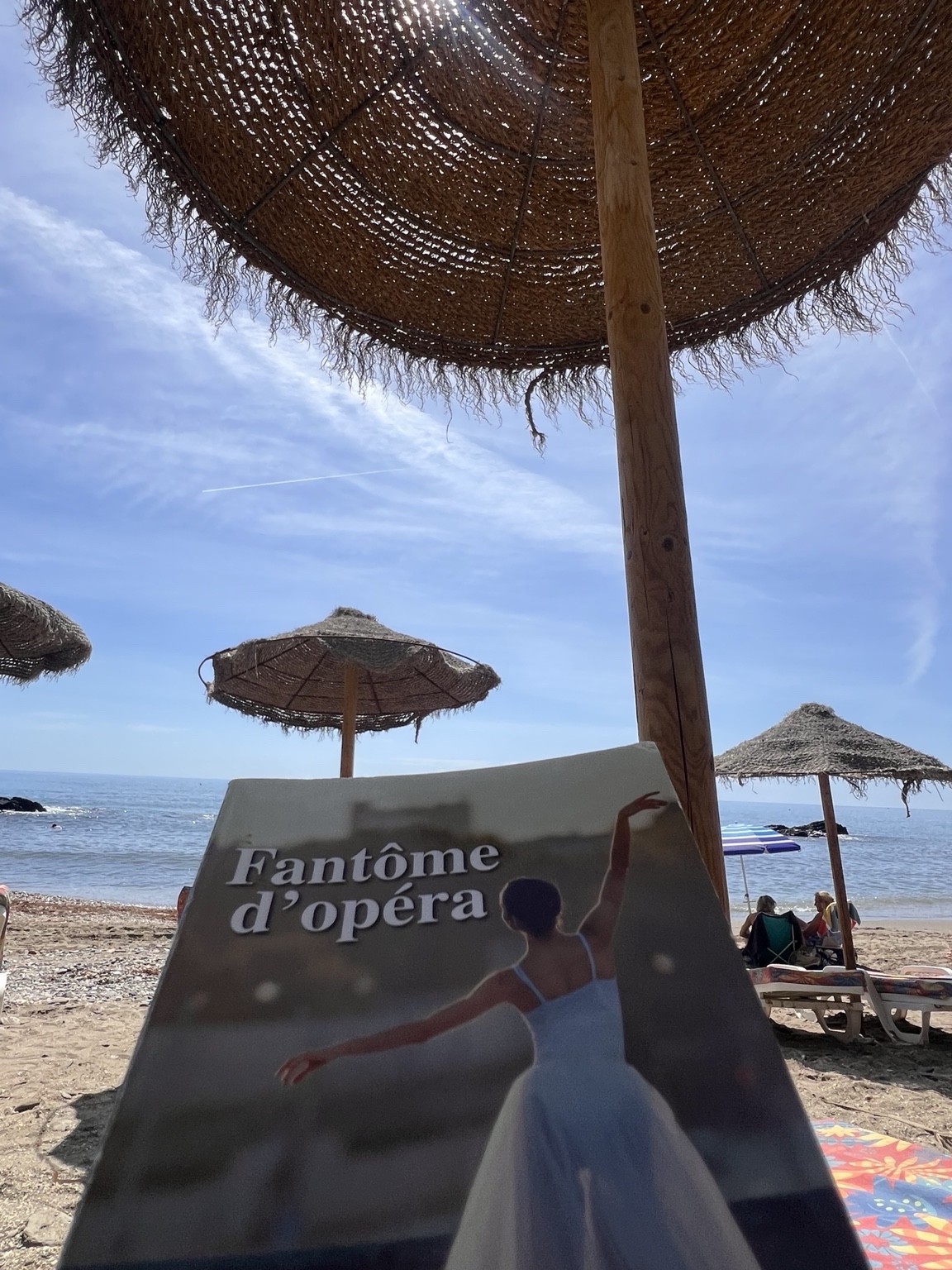 Ein Buch unter einem Sonnenschirm am Strand.
